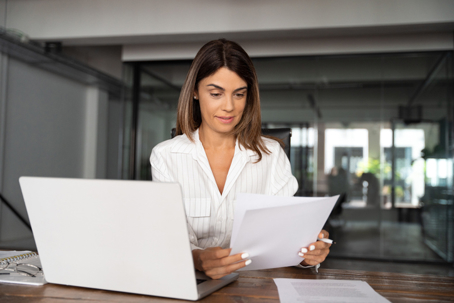 woman reviewing documents in front of laptop