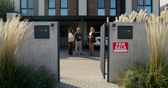 couple with real estate agent looking at a house for sale